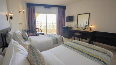 a hotel room with two beds and a mirror at JAZ Palmariva Beach in Hurghada