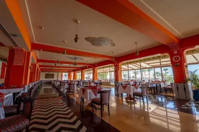 a restaurant with red walls and tables and chairs at JAZ Royal Palmariva in Hurghada