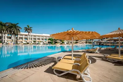 a group of chairs and umbrellas next to a swimming pool at JAZ Royal Palmariva in Hurghada