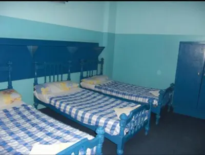 two beds in a room with blue walls at Oasis hotel in Luxor