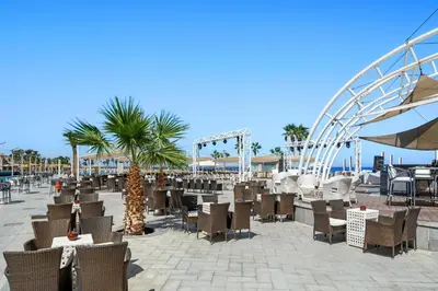 a patio with tables and chairs and a roller coaster at Pickalbatros Citadel Resort Sahl Hasheesh in Hurghada