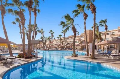 a swimming pool with palm trees and hotels at Pickalbatros Citadel Resort Sahl Hasheesh in Hurghada
