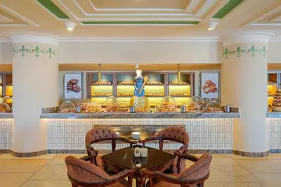 a restaurant with a table and chairs in front of a counter at Pickalbatros Citadel Resort Sahl Hasheesh in Hurghada