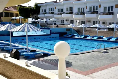 a swimming pool with chairs and umbrellas next to a hotel at Sand Beach Resort in Hurghada