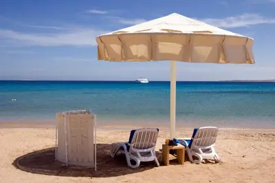 two chairs under an umbrella on the beach at Old Palace Resort Sahl Hasheesh in Hurghada