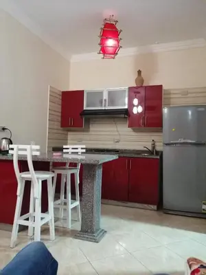 a kitchen with red cabinets and a counter with stools at Nour Plaza Hurghada Studio Sea view in Hurghada