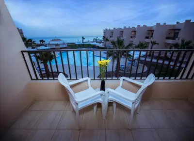 a balcony with two chairs and a table with a vase of flowers at Sky View Suites Hotel in Hurghada