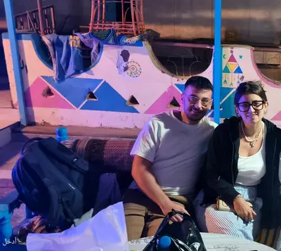 a man and a woman sitting in front of a climbing wall at Awi Guest House in Aswan