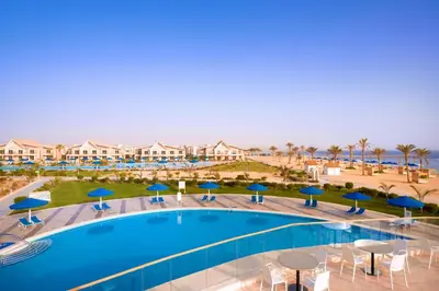 a pool with blue umbrellas and tables and chairs at Pickalbatros Sea World Resort - Marsa Alam- 