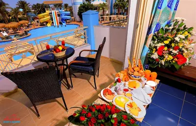 a balcony with a table with food and a pool at Mirage Bay Resort & Aqua Park in Hurghada