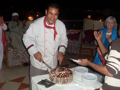a man cutting a cake with a sword at Kareem Hotel Luxor in Luxor
