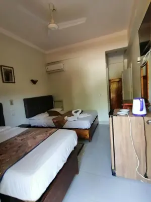 a hotel room with two beds and a desk at Rezeiky Hotel & Camp 您在盧克索的第二個家 in Luxor