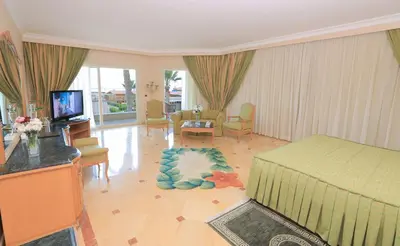 a living room with a bed and a living room with a television at Sea Star Beau Rivage Hotel in Hurghada