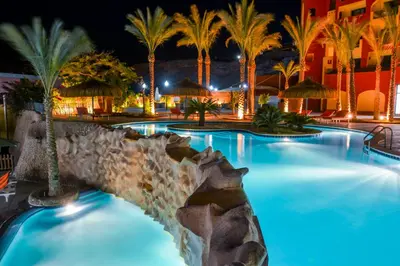 a swimming pool at night with palm trees at Sun & Sea Hotel and Aqua Park - Hurghada in Hurghada