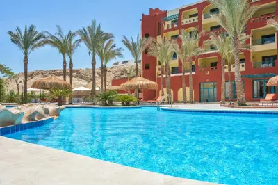 a swimming pool in front of a hotel with palm trees at Sun & Sea Hotel and Aqua Park - Hurghada in Hurghada