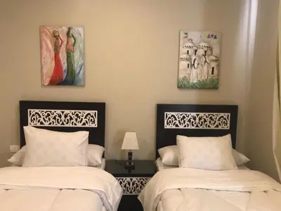 two beds in a room with paintings on the wall at Joubal Apartment in Hurghada