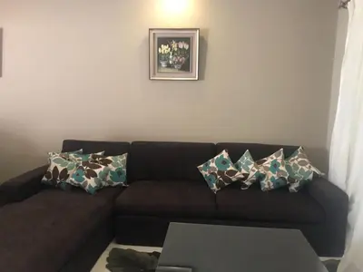 a living room with a brown couch with pillows at Joubal Apartment in Hurghada