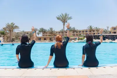a group of three women sitting on the edge of a pool at Blend Elphistone Resort Marsa Alam in Abu Dabab