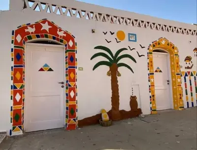 a building with two doors and a palm tree painted on it at Old Nubian guest house in Aswan