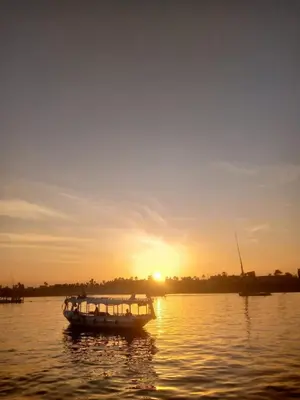 a boat on the water as the sun sets at Nile Sunrise Flats And Rooms in Luxor