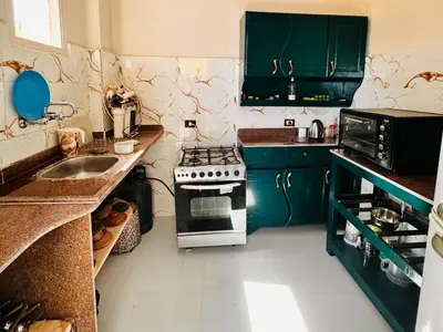 a kitchen with green cabinets and a stove top oven at Nuba Dool in Aswan
