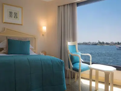 a hotel room with a bed and a chair and a window at Steigenberger Regency Nile Cruise - Every Saturday from Luxor for 07 & 04 Nights - Every Wednesday From Aswan for 03 Nights in Luxor