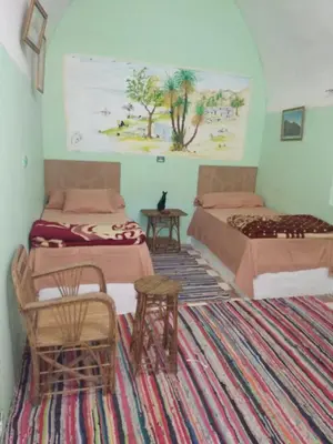 a room with two beds and a table and chairs at Aswan Nubian House in Aswan