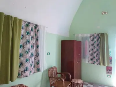 a room with two chairs and a cabinet and curtains at Aswan Nubian House in Aswan