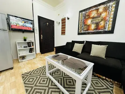a living room with a black couch and a table at Karibu House Sheraton Road in Hurghada