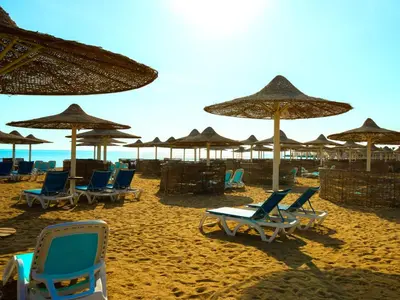 a group of chairs and umbrellas on a beach at Stella Gardens Resort & Spa, Makadi Bay in Hurghada
