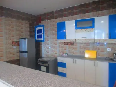 a kitchen with blue and white cabinets and a refrigerator at Moon Valley Apartments in Luxor