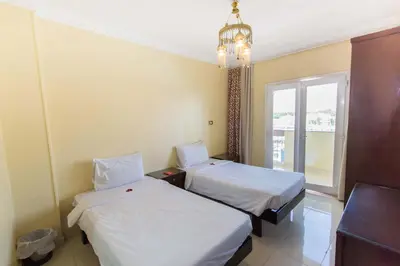 a hotel room with two beds and a chandelier at Philae Hotel Aswan in Aswan
