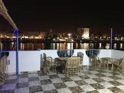 a table and chairs on a deck with a view of the water at Nubian Paradise in Aswan