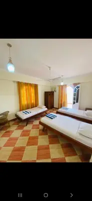 a large room with three beds and a checkered floor at Leyla Eco Resort in Luxor