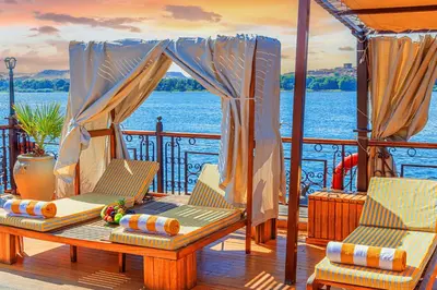 a deck with two chairs and a table on a boat at Sonesta Dahabeya Amirat I - Nile Cruise Ship From Luxor to Aswan 7 nights in Luxor
