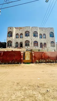 a large white building with windows in a dirt field at Memnoun house in Luxor