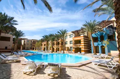 a swimming pool with lounge chairs and palm trees at Marina Residence Suites Port Ghalib in Port Ghalib