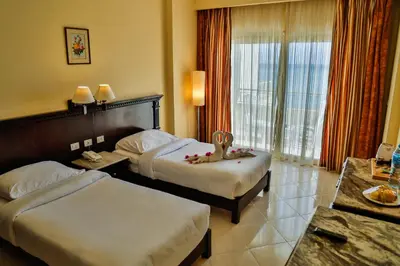 a hotel room with two beds and a window at Magic Beach Hotel Hurghada in Hurghada