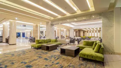 a lobby with green couches and tables in a building at Amarina Abu Soma Resort & Aquapark in Hurghada