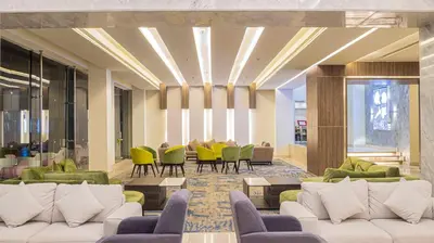 a lobby with white couches and green chairs and tables at Amarina Abu Soma Resort & Aquapark in Hurghada