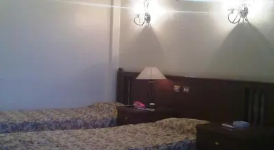 a bedroom with two beds and a lamp on a table at Orchida St. George Hotel in Aswan
