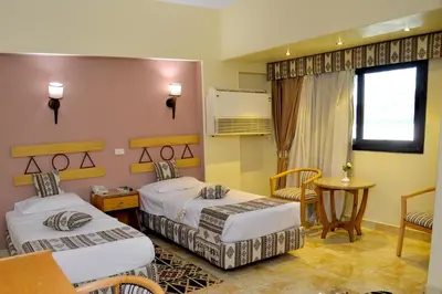 a hotel room with two beds and a table at Marhaba Palace Hotel in Aswan