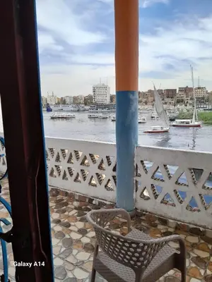 a chair on a balcony with a view of the water at NiLe ViEW RANA NUbian Guest HOUES in Aswan