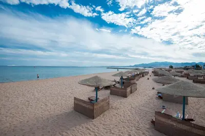 a beach with umbrellas and chairs and the ocean at Shams Safaga Resort in Hurghada
