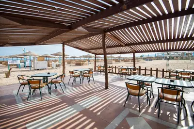 a patio with tables and chairs on a beach at Shams Safaga Resort in Hurghada