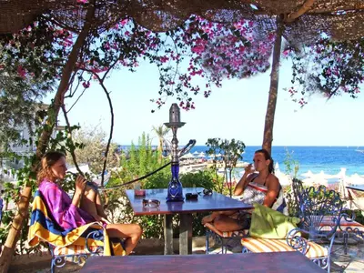 two women sitting at a table on the beach at King Tut Aqua Park Beach Resort in Hurghada