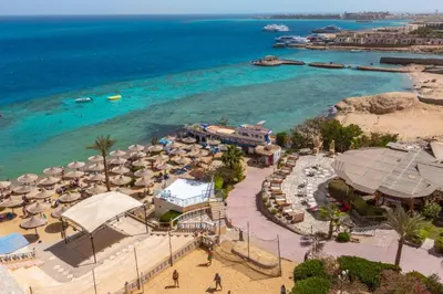an aerial view of a beach with umbrellas and the ocean at King Tut Aqua Park Beach Resort in Hurghada