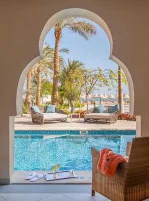 a swimming pool with a table and chairs and palm trees at Grand Palace - Couples only 18 years plus in Hurghada
