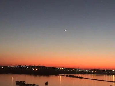a moon in the sky over a lake at sunset at Villa Misk in Aswan