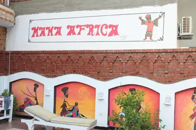 a mural on the side of a brick building with a bench at Mama Africa Apts & Studios in Luxor